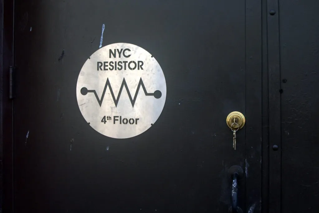 Photo of NYC Resistor's front door, featuring a steel sign with Resistor's logo.
