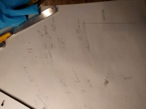 White paper fills the page. In black pen, there are lines an measurements scrawled over the page. In the upper left sits the bottom half of a pencil and a set of mechanical calipers.