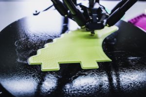 A 3d printer is printing an irregularly-shaped green object