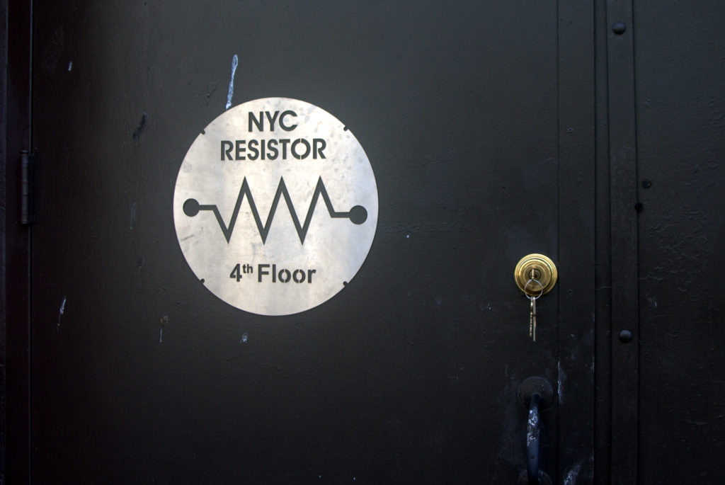 Photo of NYC Resistor's front door, featuring a steel sign with Resistor's logo.